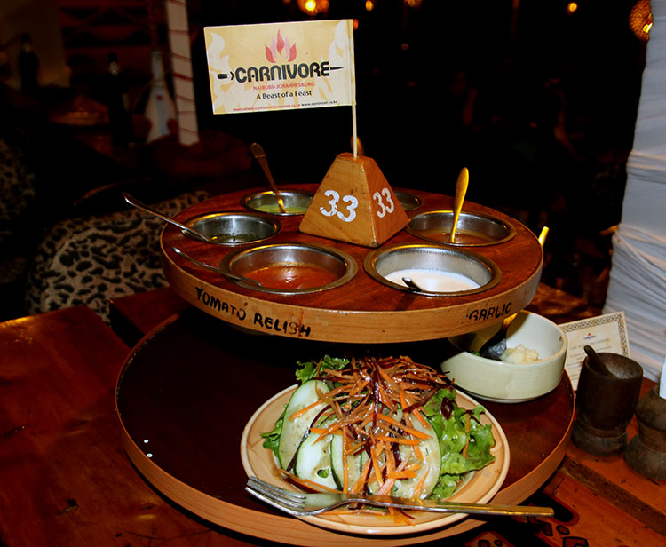The two-tier lazy susan with various sauces on the top and salads and side dishes on the bottom at Carnivore