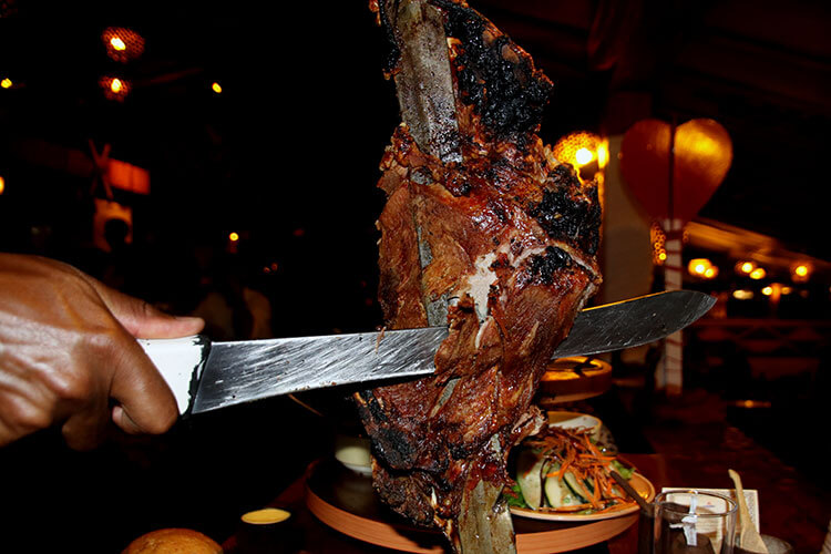 A server carves meat from a sword onto a plate at Carnivore in Nairobi