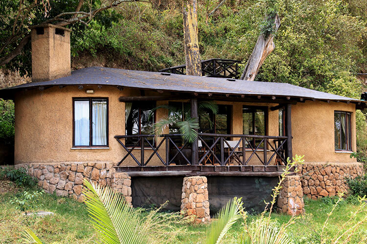 The exterior of the cottages at The Emakoko with a light brown stucco to blend in to the hillside and dark wood balcony