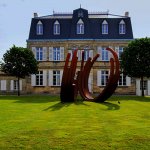 A metal sculpture sits on the lawn in front of the 19th century Château Malescasse