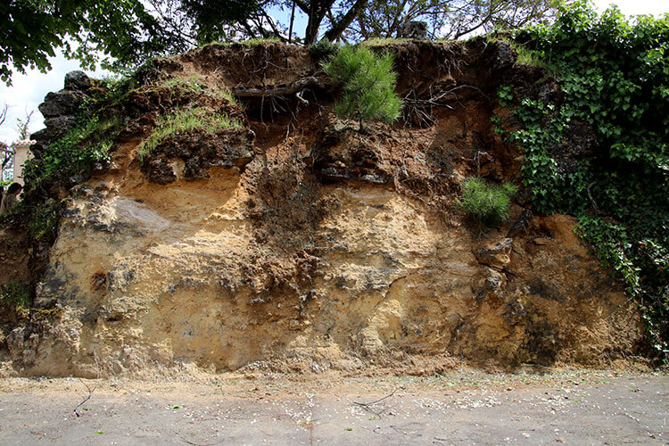 A wall of the soil layers is excavated alongside Château Tour Baladoz for visitors to see the layers