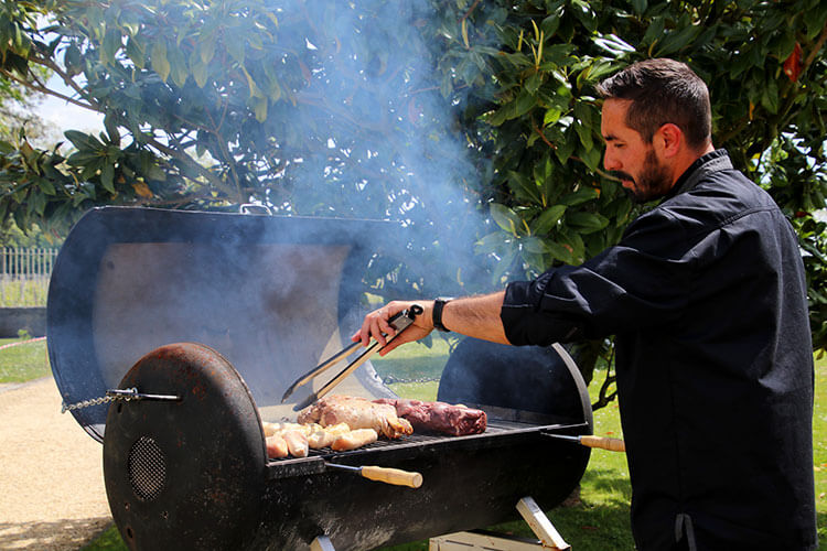 Chef grilling three kinds of meat on a barbecue at Château Malescasse