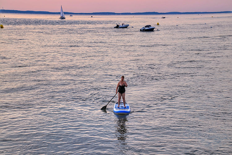 Jennifer paddle boarding in the soft pink light after sunset at the Bassin d'Arcachon