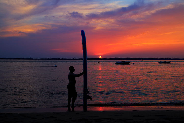 Tim holding the iSUP board vertical at sunset at Arcachon