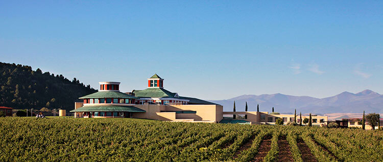 The modern and minimalistic Vivanco winery surrounded by vineyards with the mountains in the distance in La Rioja, Spain 