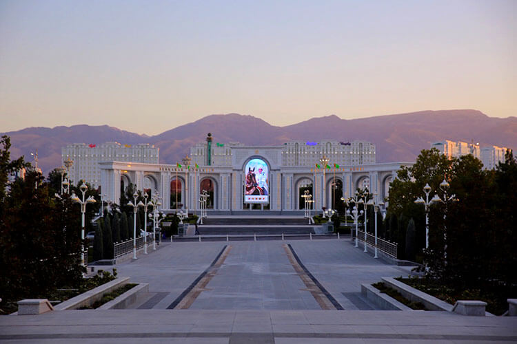Huge white marble monuments in Ashgabat tinted pink in the sunset