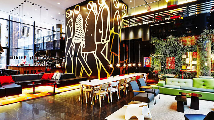 The "living room" of the citizenM Times Square with communal tables to relax or work at and a fireplace