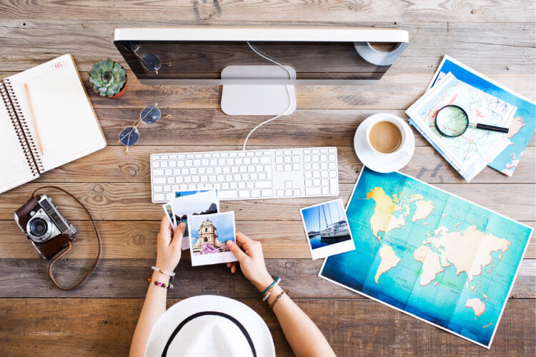 An overhead view of a person doing research on an iMac with a map on the desk