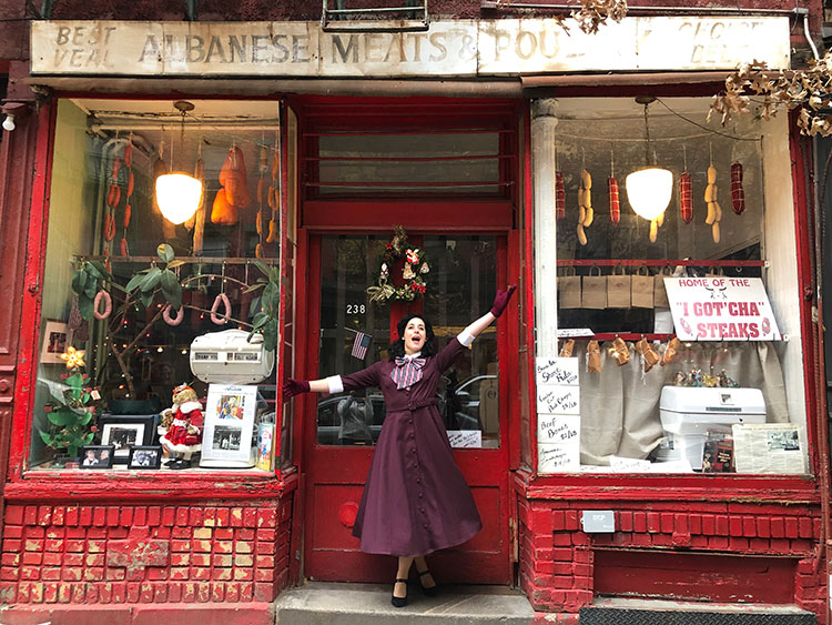 One of the guides dresses up and poses outside a butcher shop on the Marvelous Mrs. Maisel tour in New York City