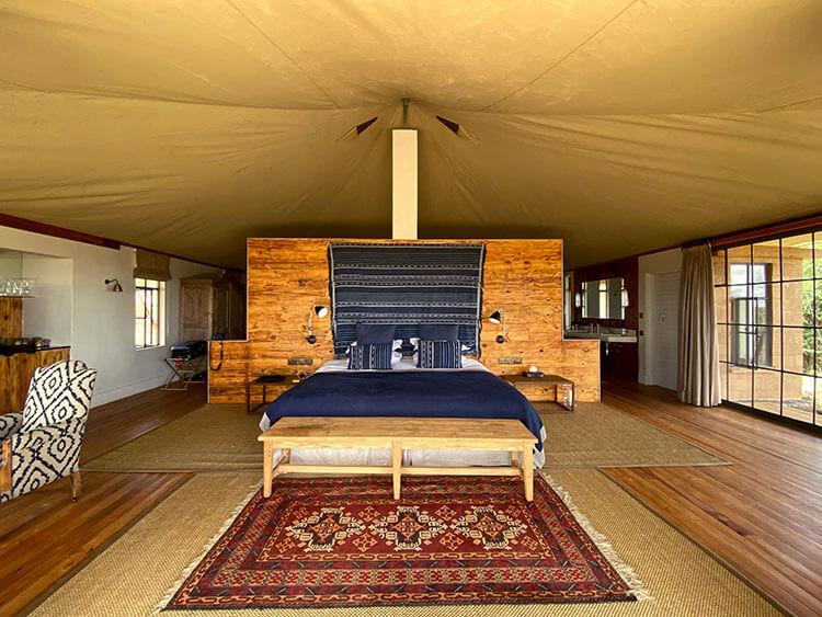 Inside the tent with king size bed, simple decor and a sitting area at Loisaba Lodo Springs