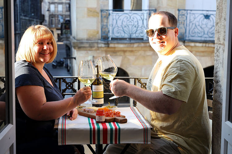 Jennifer and Tim sitting on the balcony with wine and a charcuterie board in Bordeaux