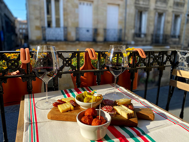 Our apéro spread on our balcony with accras, pickled Espelette peppers, cheese, charcuterie and wine on our balcony in Bordeaux, France