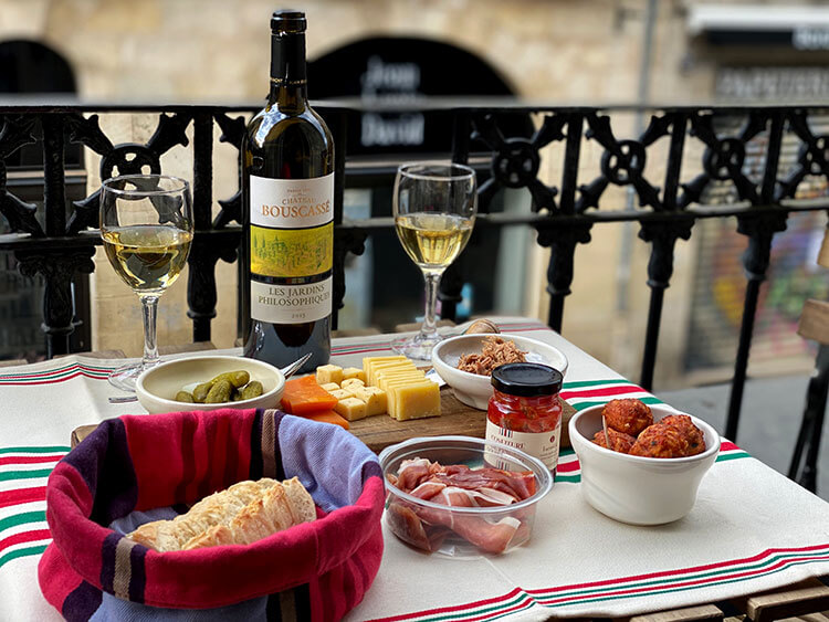 Our balcony apéro spread with accras, cheese, saucisson, pickles, bread and wine in Bordeaux, France
