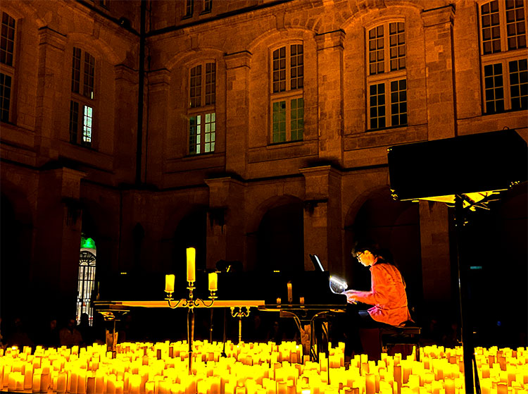 A Candlelight Concert with a stage in the center of Cour Mably illuminated by candlelight