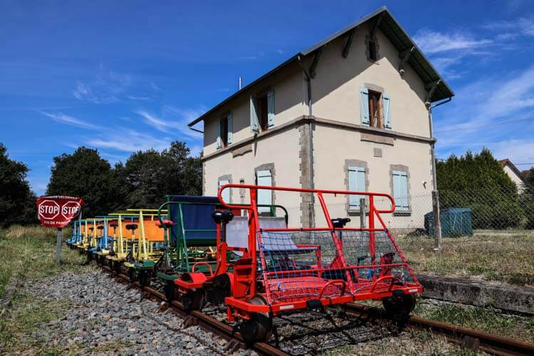 Red, green and yellow rail bikes lined up at the Bosmoreau-les-Mines historic railway station 