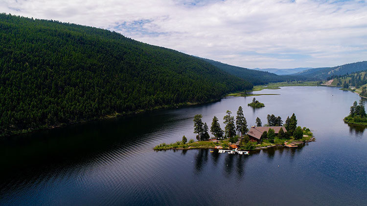 An aerial of the Island Lodge located on a small island in the middle of a lake at Paws Up Resort Montana