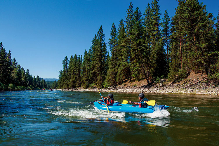 A couple paddles a canoe on the river near Paws Up Resort Montana