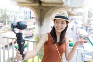A girl holds a selfie stick to film herself on video