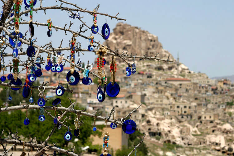 Turkish eye beads hand on a tree at a viewpoint looking out to the fairy chimneys of Cappadocia, Turkey