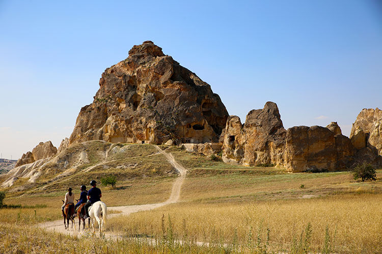 Three people on horseback on a trail in Geronme National Park in Cappadocia, Turkey