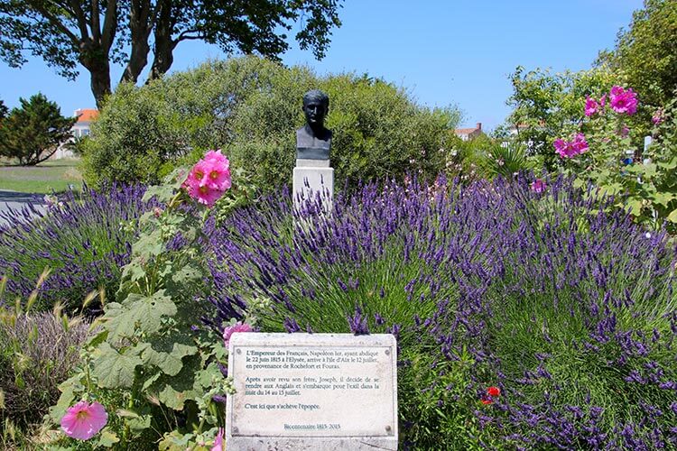A bust of Napoleon sits amid a small garden with roses and lavendar on Île d'Aix