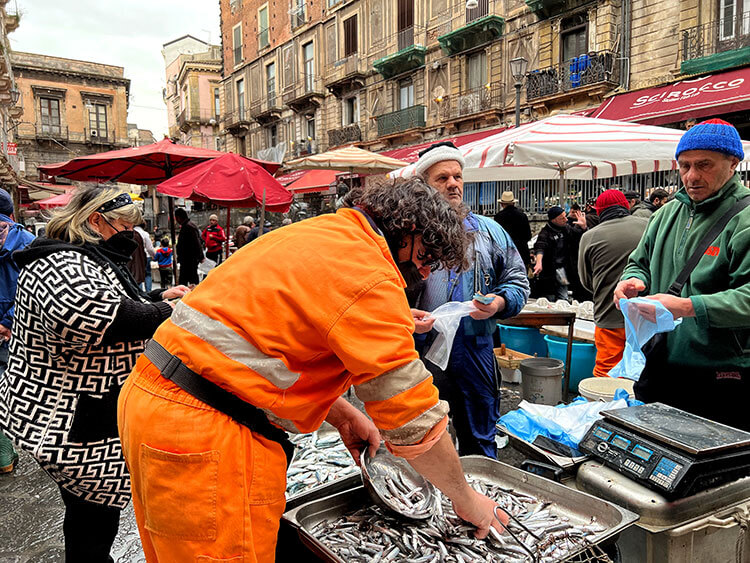 Customers haggle with a fisherman for some fish at La Pescheria in Catania, Sicily
