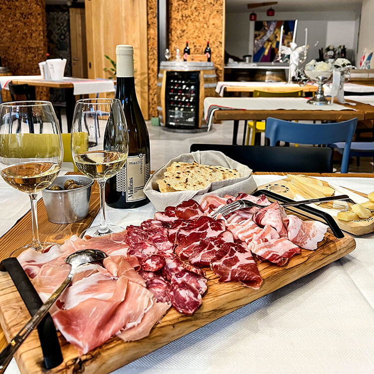 A board of cured meats and cheese with Vermentino wine at Cantina Mastìo Hofmann in Galtellì, Sardinia