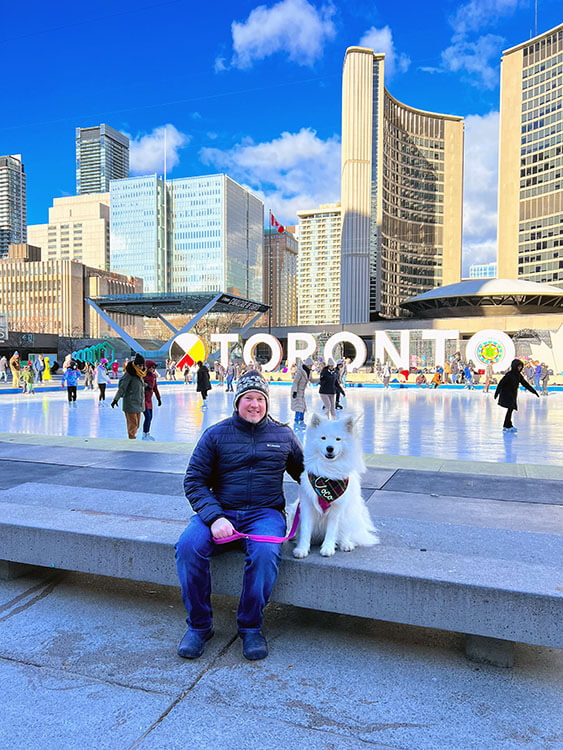Tim and Coco sit watching ice skaters on the outdoor rink under the Freedom Arches at Nathan Phillips Square