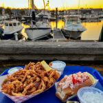 Clam strips and Connecticut-style hot lobster roll served with coleslaw and tartar sauce at sunset at Captain Scott's Lobster Dock in New London, Connecticut