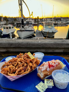 Clam strips and Connecticut-style hot lobster roll served with coleslaw and tartar sauce at sunset at Captain Scott's Lobster Dock in New London, Connecticut
