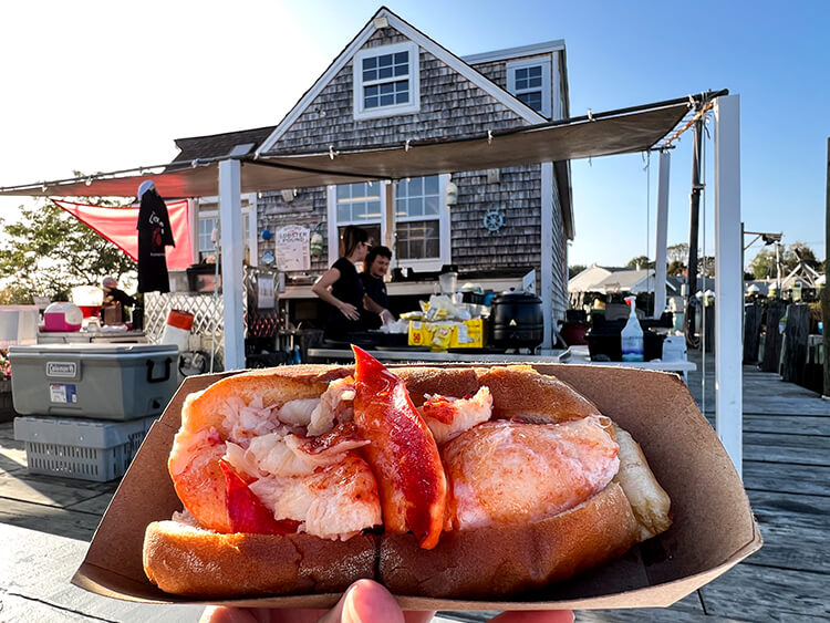Holding up a Connecticut-style lobster roll at Guilford Lobster Pound in Guilford Connecticut