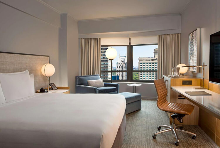 New York Hilton Midtown hotel room with king bed, chaise lounge chair and city view