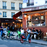 The restaurant Le Pipos with its' red awning, and customers enjoying apero at the outdoor tables in Paris' Latin Quarter