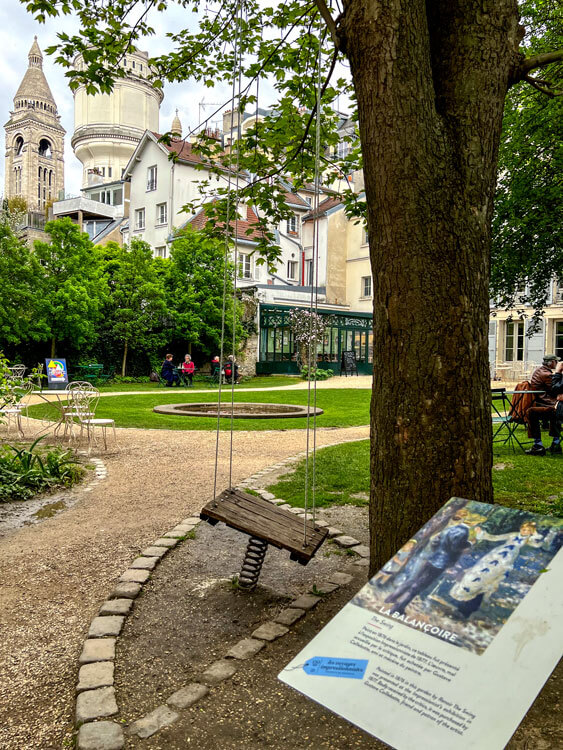 The swing in the gardens of the Musée de Montmartre with a sign next to it explaining Renoir's famous painting The Swing was painted in the gardens