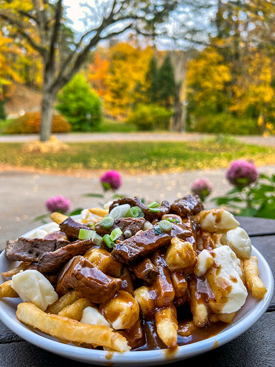 Prime rib poutine with thick cut steak fries, cheese curds and piece of prime rib beef on the verandah at Caroline's at the Glen Iris Inn in Letchworth State Park