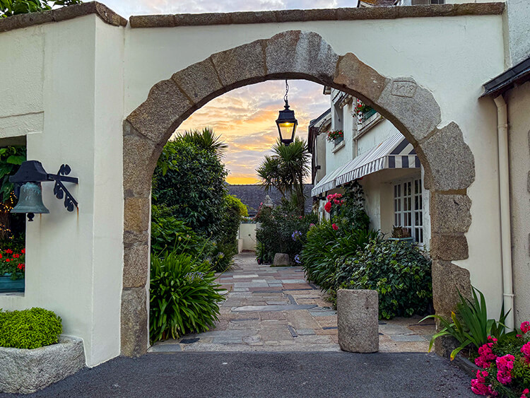 A stone archway leading in to the garden at sunset at Domaine de Rochevilaine