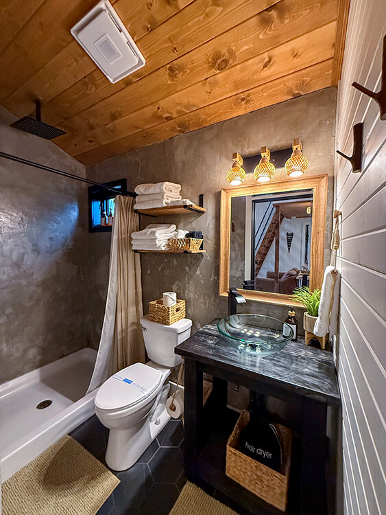 The bathroom has a rain shower and is equipped with a smart bluetooth speaker