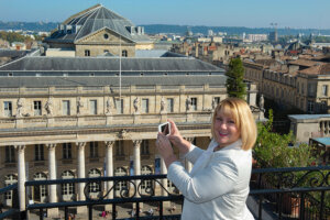 Jennifer holds her iPhone to take a photo of the Bordeaux skyline from the rooftop of the Grand Hotel