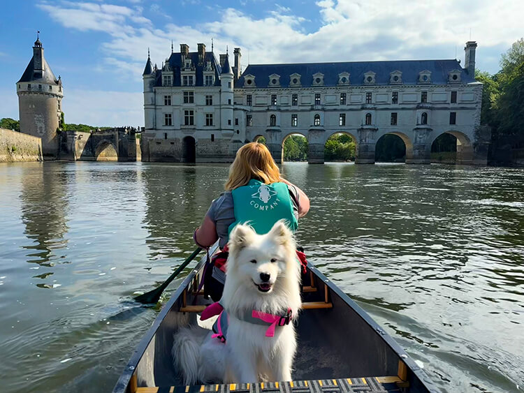 Coco sits in the canoe as Jennifer paddles toward Canoeing on the River Cher at Château de Chenonceau on the River Cher in the Loire Valley
