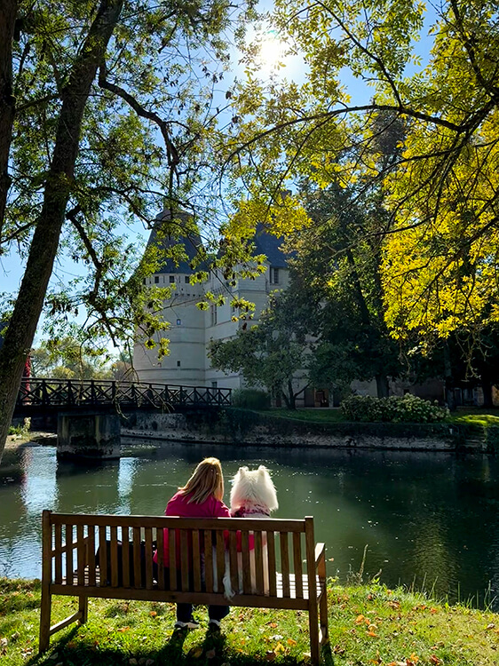 Jennifer and Coco sit on a bench in the park of Château de l'Islette admiring the castle in the Loire Valley