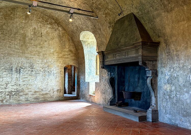 A large fireplace dominates an otherwise empty room of the Castello di Serralunga