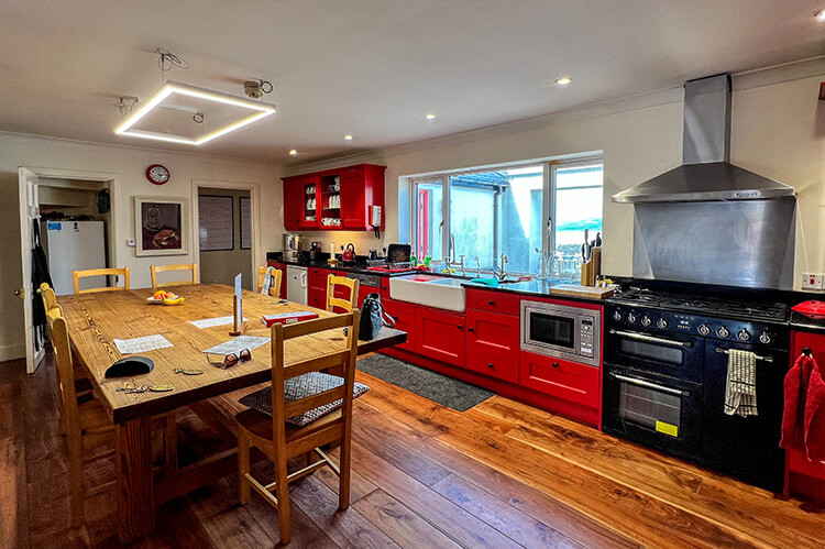 The well-equipped kitchen with wood dining table, 5 burner Smeg cooktop and oven, and sea view at Clare Island Lighthouse