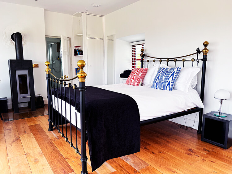 The wrought iron bed and woodburning stove in the Sauna Suite at Clare Iron Lighthouse