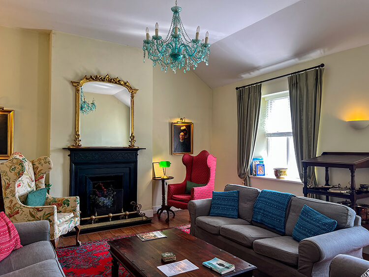 The drawing room with fireplace, Venetian glass chandelier, and period furniture at Clare Island Lighthouse