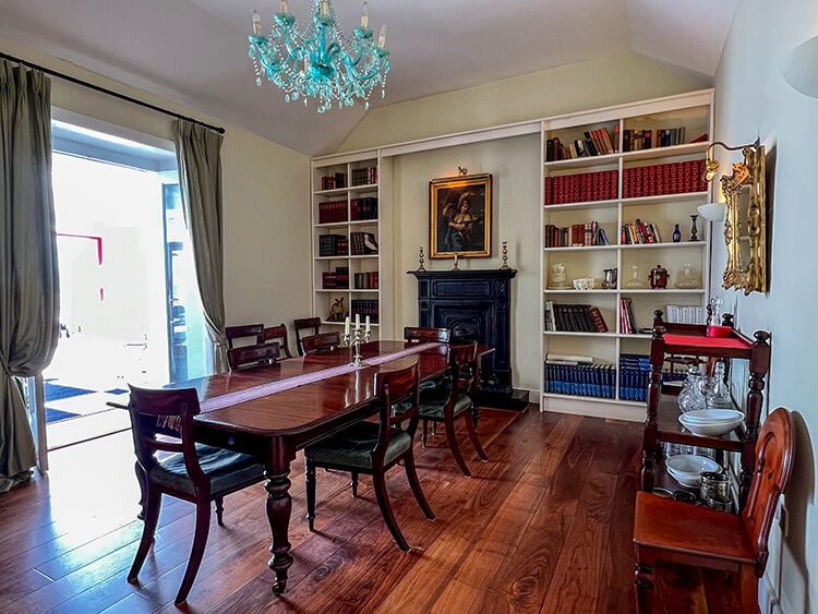 The formal dining room with mahogany dining table, Venetian glass chandelier and library of books lining the walls at Clare Island Lighthouse