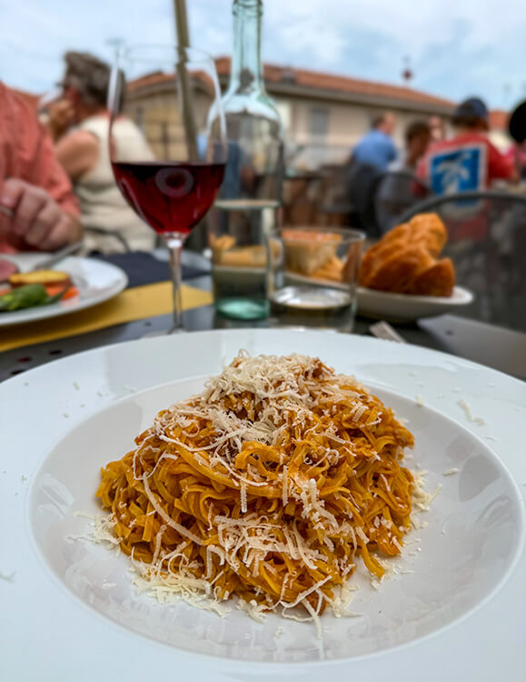 A pasta bowl of tajarin al ragu with a glass of Barbareso at Osteria More e Macine in La Morra