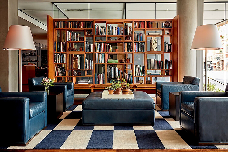 The library living room at The Study at Yale with bookcases and navy leather reading chairs